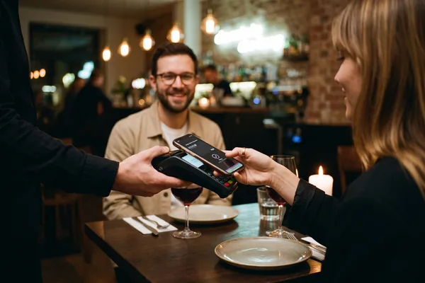 Gast bezahlt entspannt mit dem Smartphone im Lieblingscafé